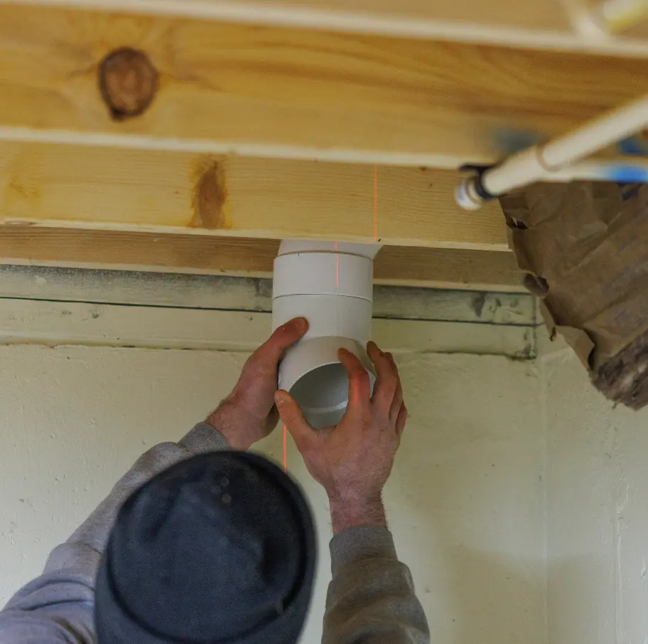 Person installing duct under wooden ceiling.