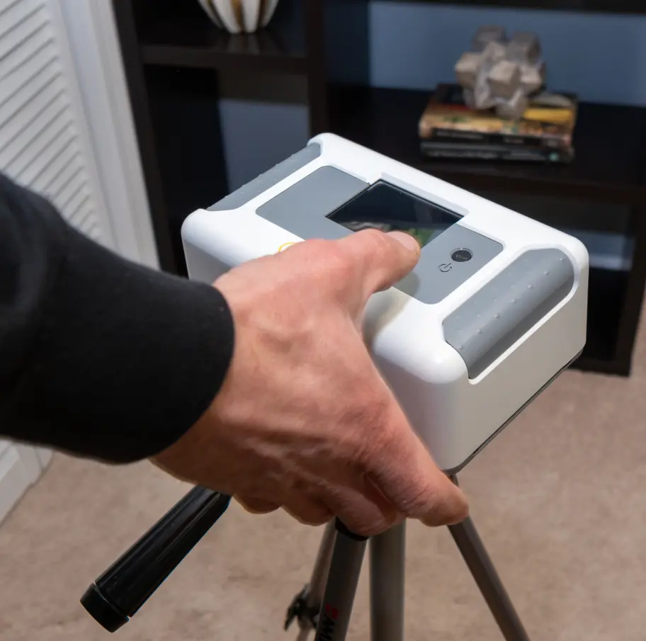 Hand adjusting device on tripod indoors.